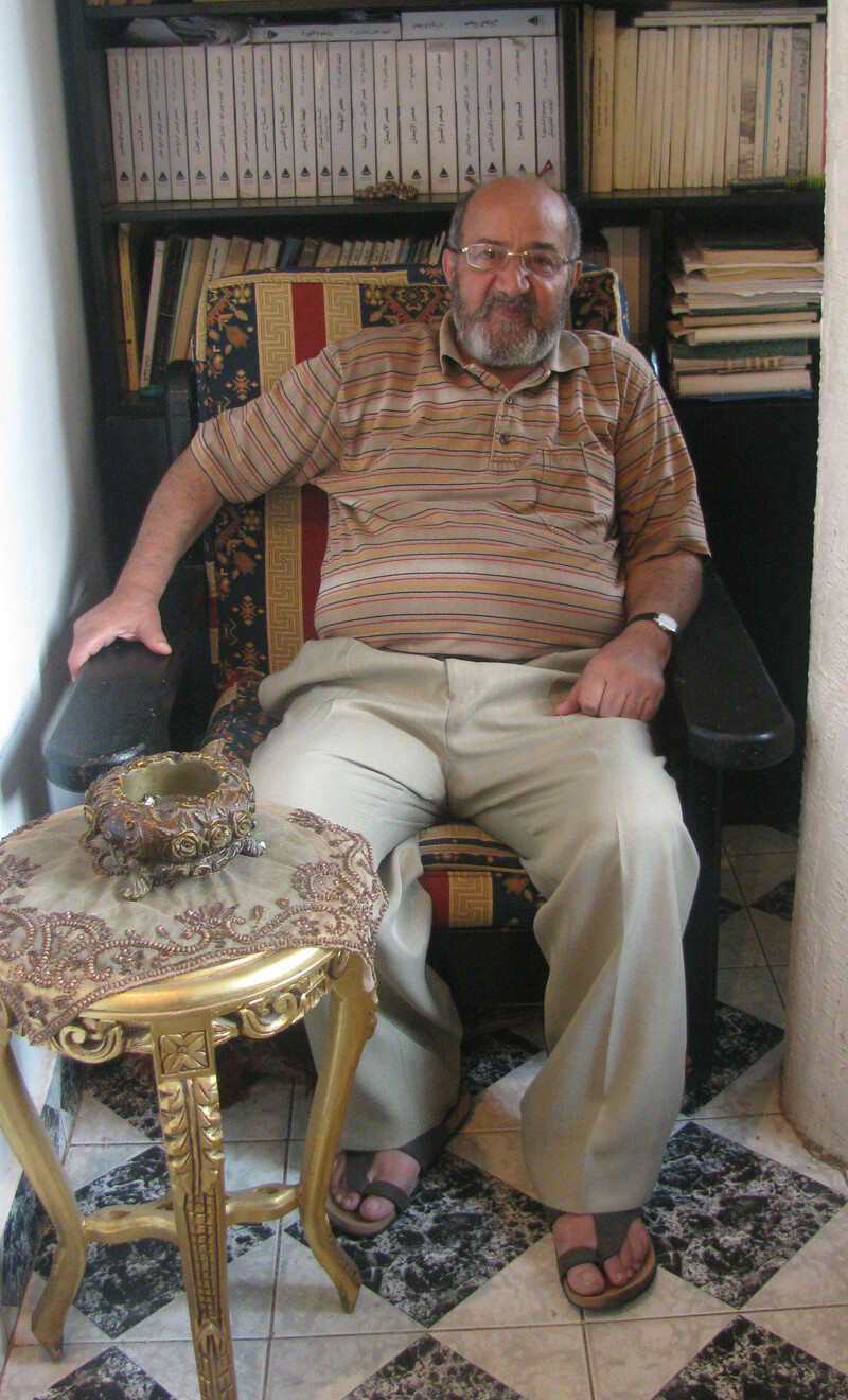 Smiling man sits in front of book case