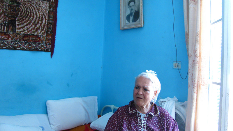 Elderly woman sits in brightly-colored room
