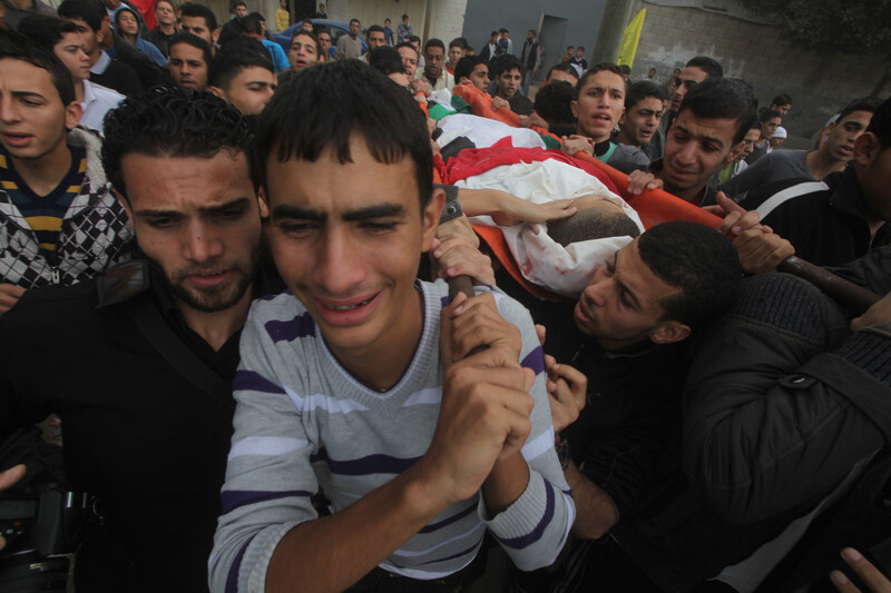 Young men carry body of slain man in funeral procession.