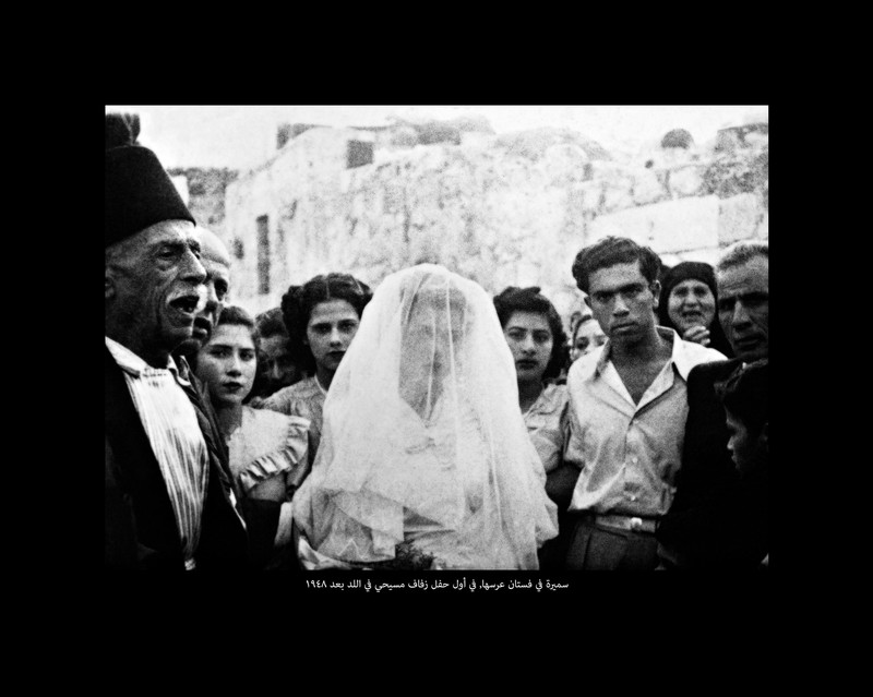 Black and white image of bride in white dress and veil surrounded by people