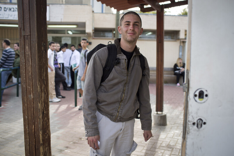 Smiling young man stands in front of building