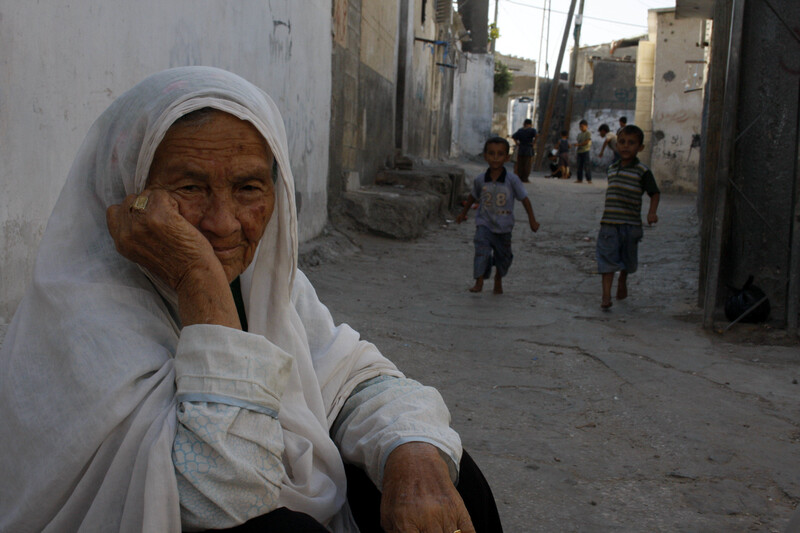 Elderly woman sits in refugee camp