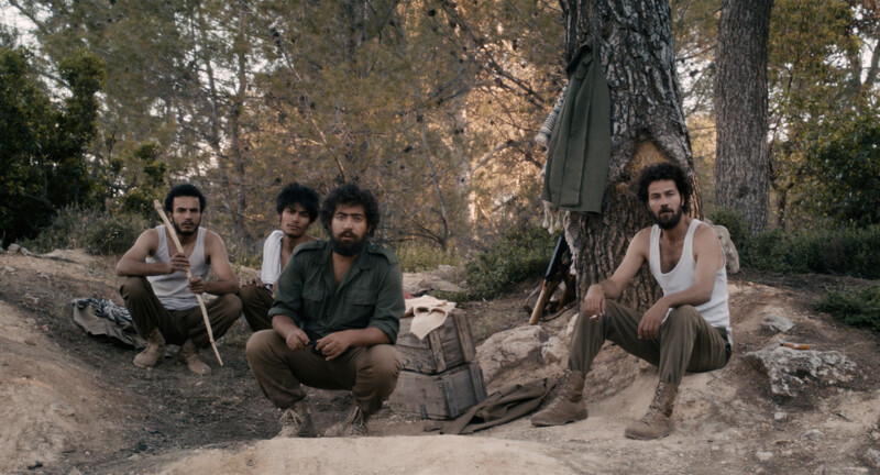 Men in military clothes sit in forest camp