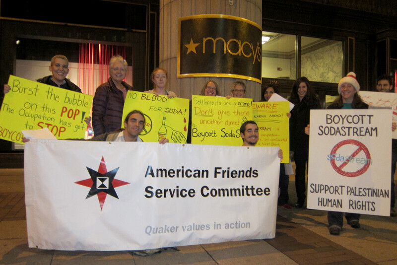 Protesters hold signs urging boycott of Sodastream products in front of Macy's