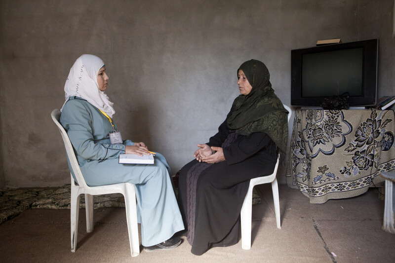 Women sitting on plastic chairs face one another