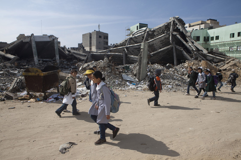 Children walk past rubble of destroyed buildings