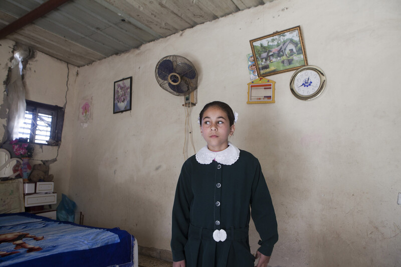 Girl stands in modestly decorated room