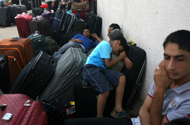 Men and boys sleep on suitcases