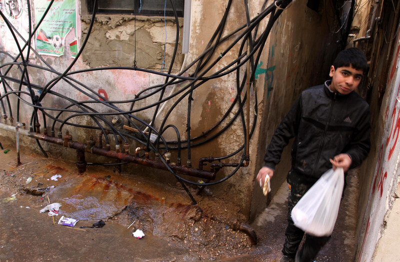 Youth walks in narrow alleyway where lots of electrical cables hang