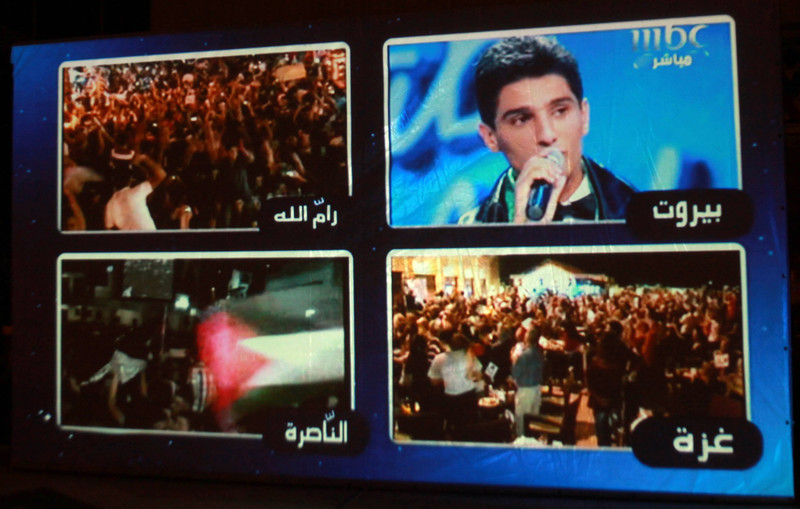 Photograph of projection of split-screen footage of people celebrating