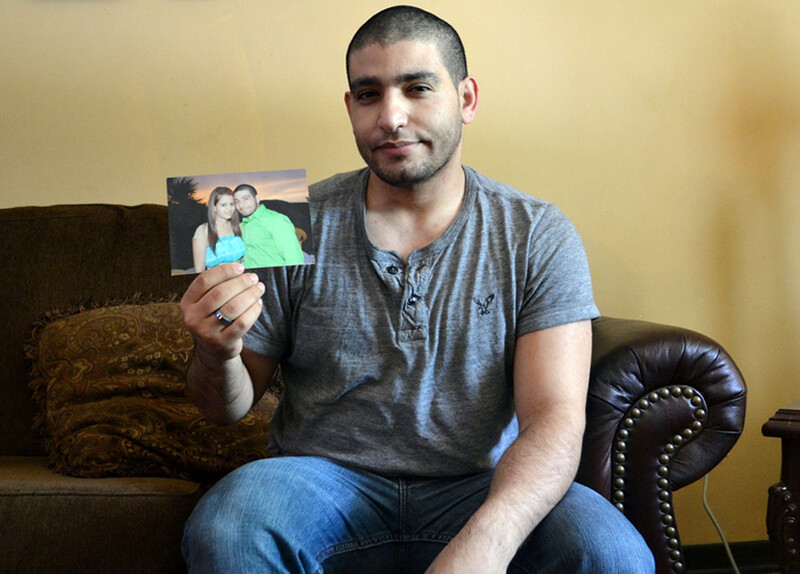 Man sitting on couch holds photo of him and young woman embracing