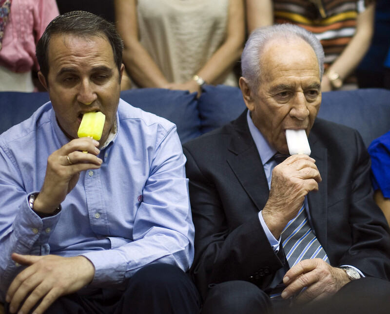 Two men, including Israeli president Shimon Peres, appear unhappy while eating ice cream