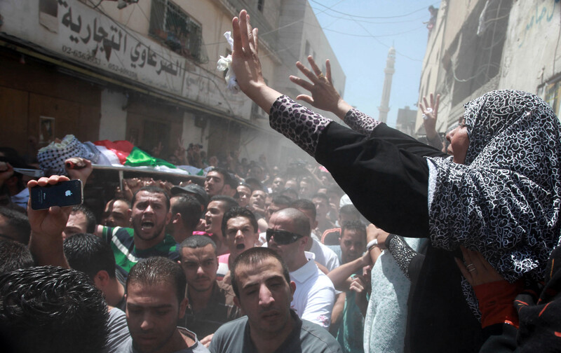 Woman raises her hands above passing funeral procession