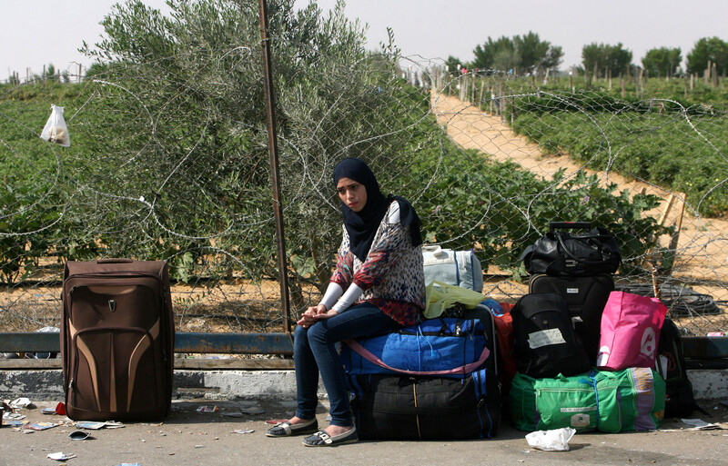 Young woman looks unhappy as she sits outdoors among suitcases