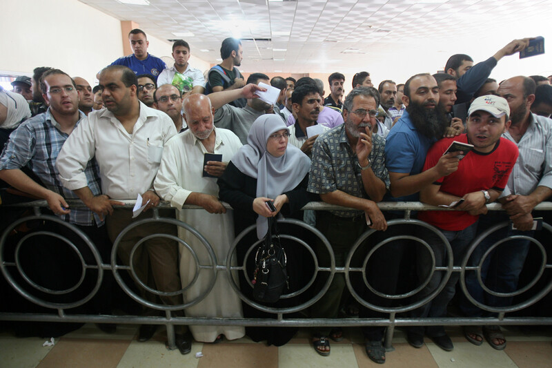 A crowd of people waving passports and travel documents