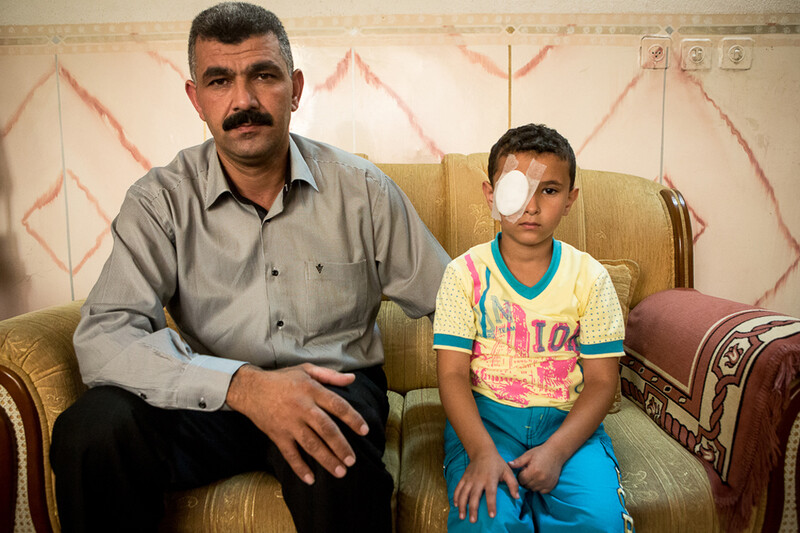 Man sits next to boy wearing cotton bandage eye patch