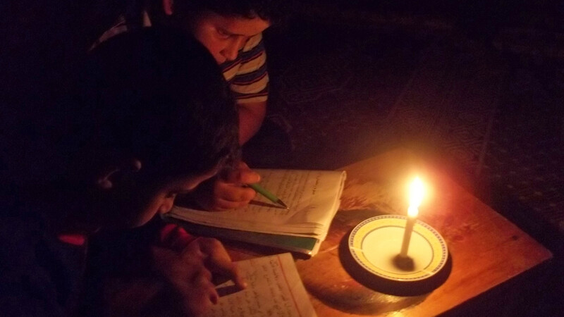 A Palestinian boy poses behind candles during a power outage