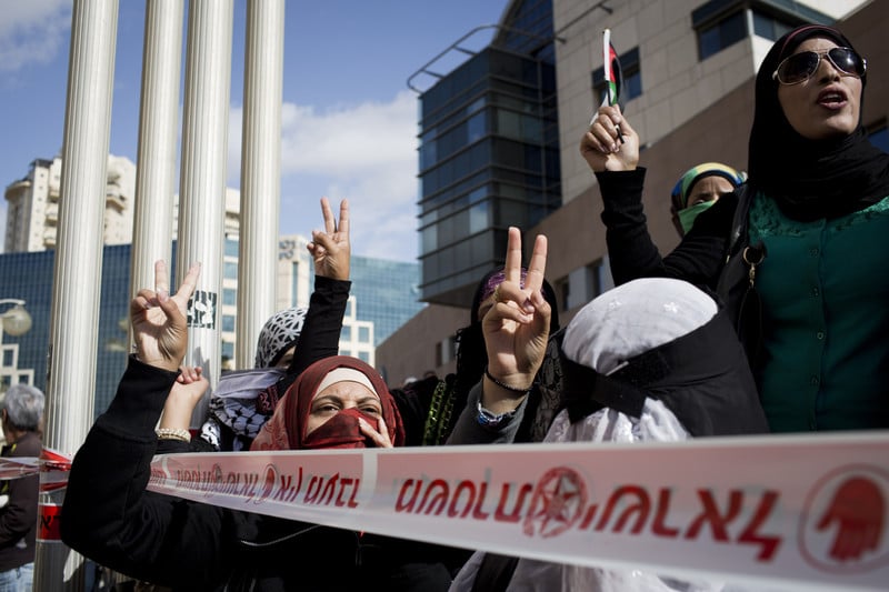 Women make victory sign with their hands during protest