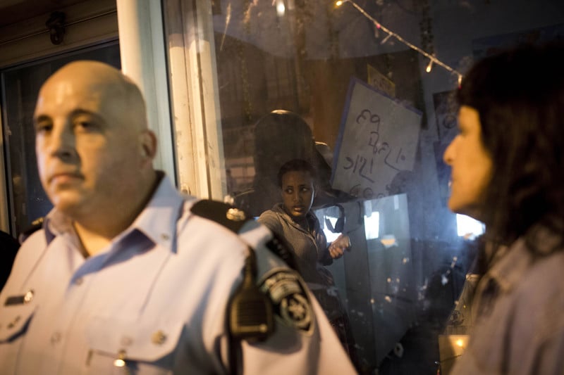 Woman cowers in storefront as Israeli police stand outside