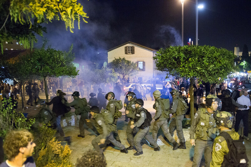 Riot gear police wearing army type uniforms chase demonstrators