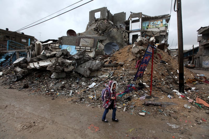 Girl walks in front of bombed-out building