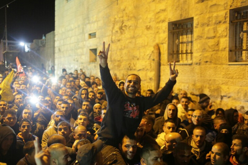 Young man is carried on another man's shoulders in middle of large crowd