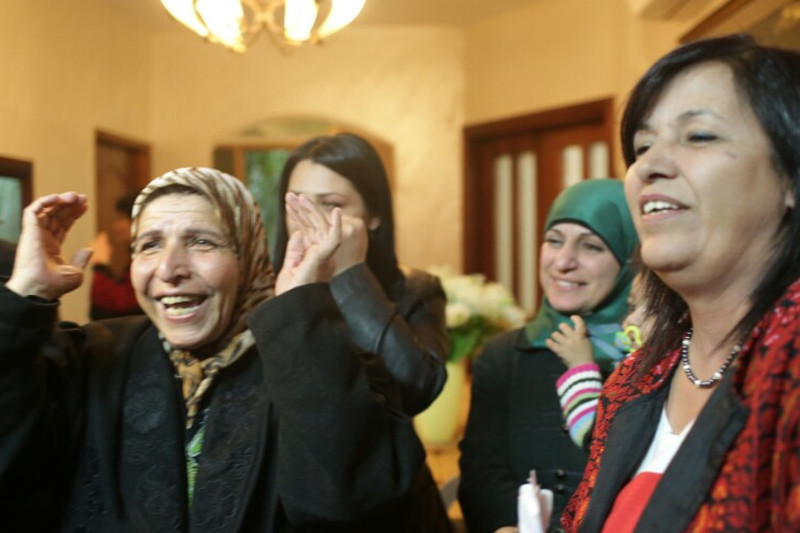 Women of different generations tearfully smile and gesture with their hands