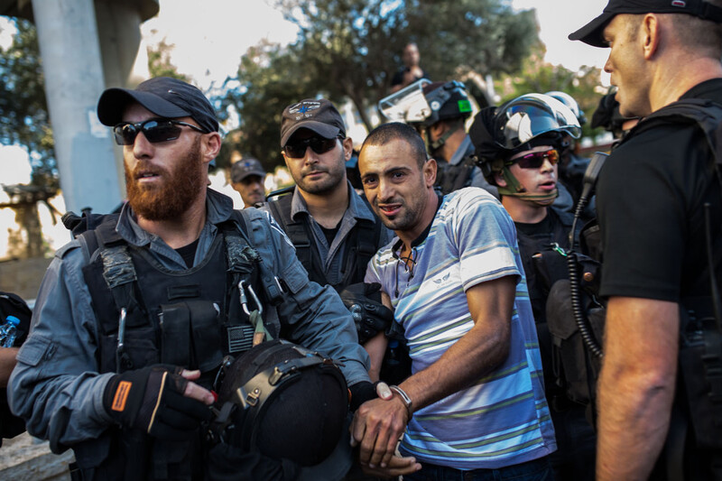 Israeli forces in riot gear arrest young man with blood smeared on his mouth