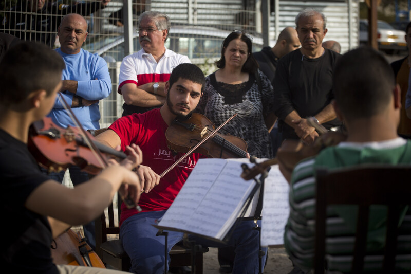 Young man plays the viola as others look on