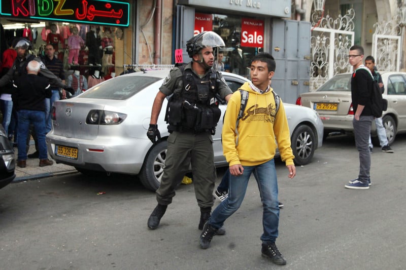 An Israeli soldier arrests a Palestinian child.