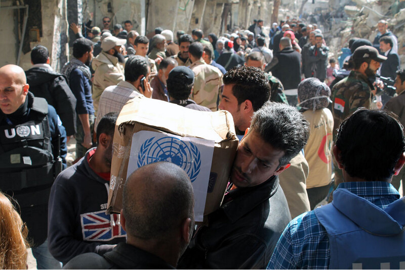 Man carries box of UN provisions amid crowd