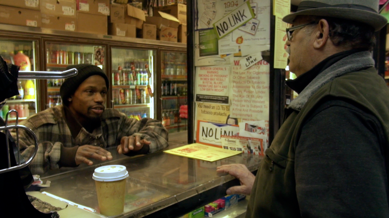 Young African American man talks to store owner with a tall counter separating them