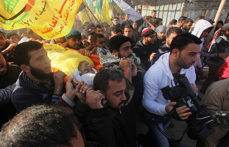 Men carry body of young man wrapped in yellow flag