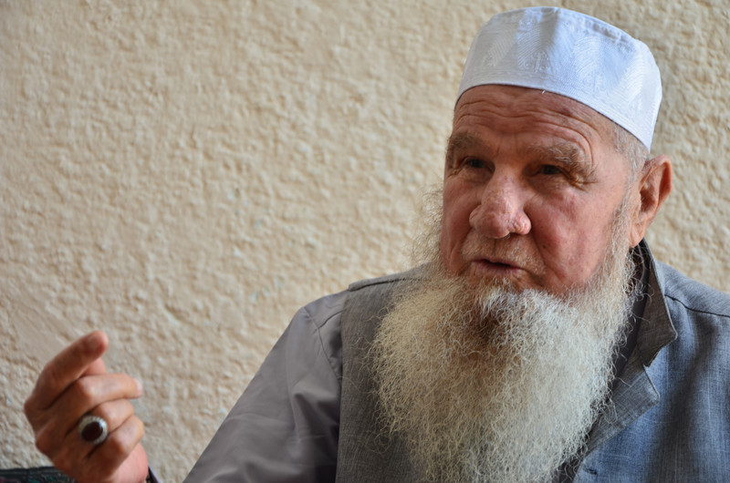 Close-up portrait of elderly man with full white beard and white skullcap