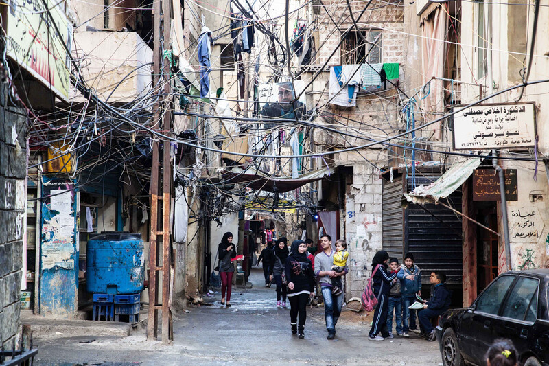 Scene of overcrowded refugee camp with cement buildings and lots of electricity wires