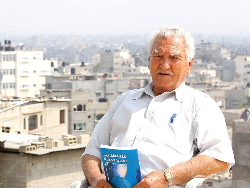 Elderly man sits on rooftop while holding book