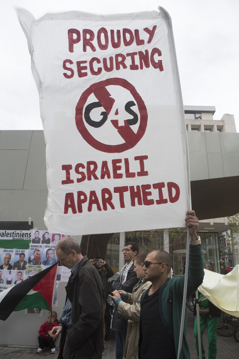 Young man at protest holds sign protesting G4S