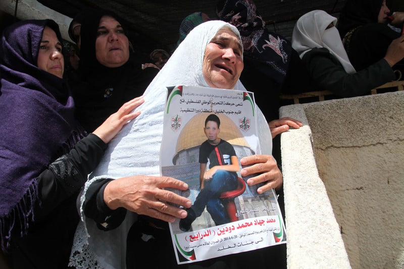 Mourning woman holds poster of slain child