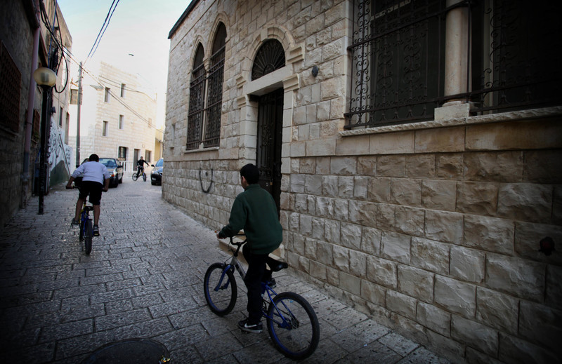 Boys ride bicycles through old neighborhood of Tarshiha