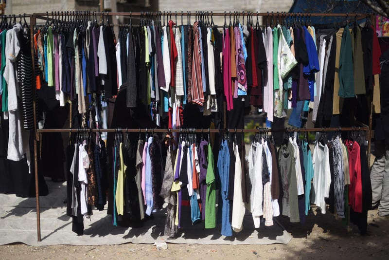 A rack of used clothing in an open-air market