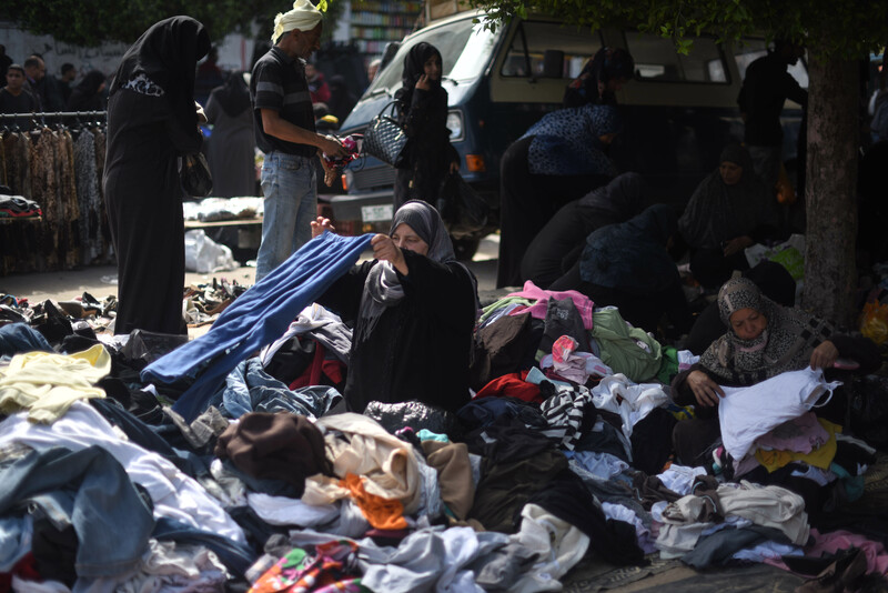 Woman inspects pair of jeans in open air clothing market