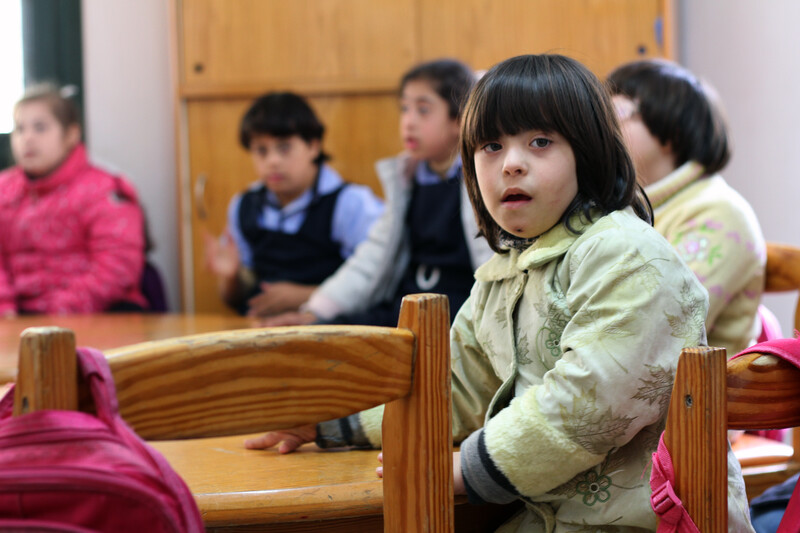 Close-up of girl sitting at desk with fellow schoolgirls