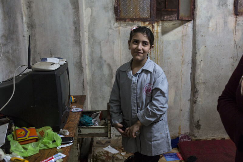 Smiling girl stands in room with unpainted walls