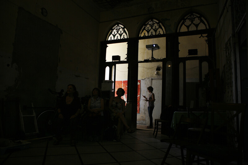 Silhouetted figures stand in arched doorways