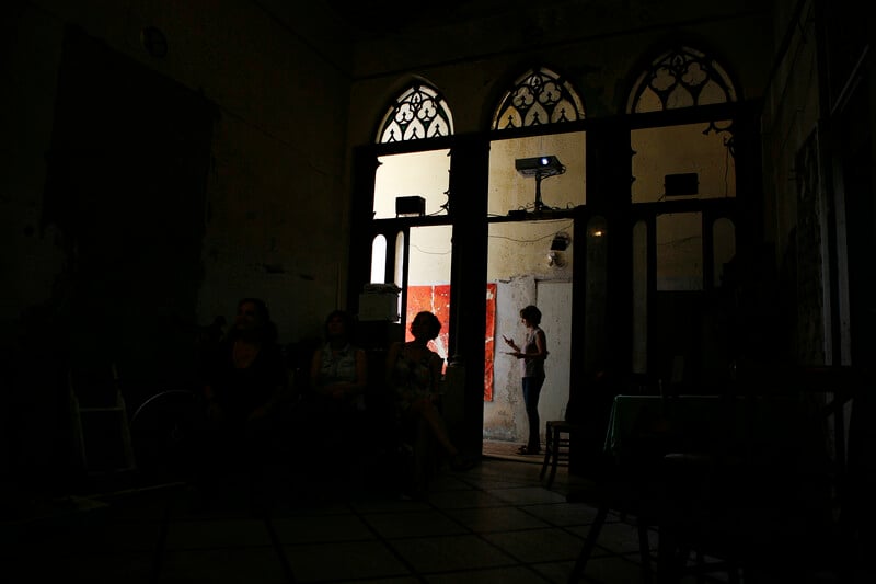 Silhouetted figures stand in arched doorways