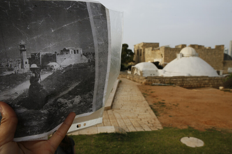 A black and white photograph of the historic mosque is held in front of present-day mosque