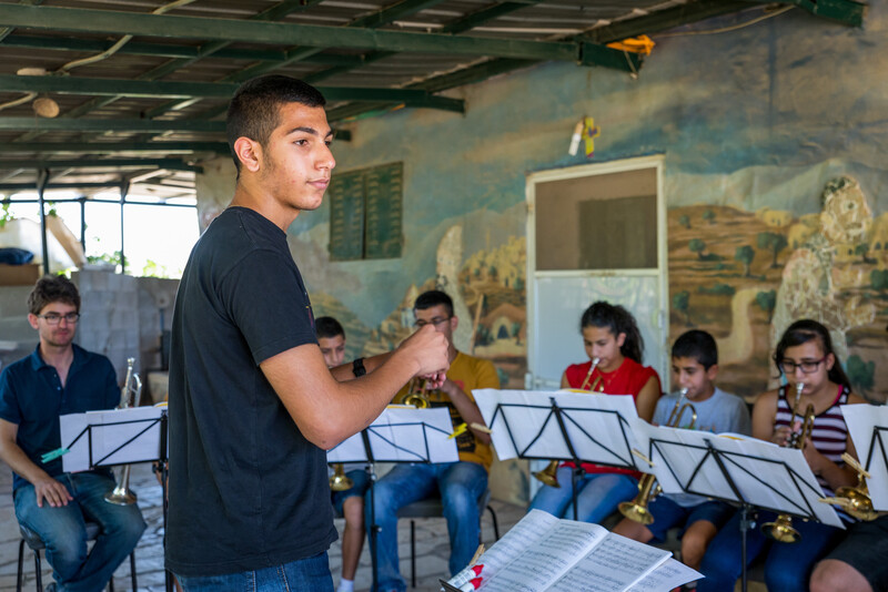 Boy conducts group of children playing trumpets