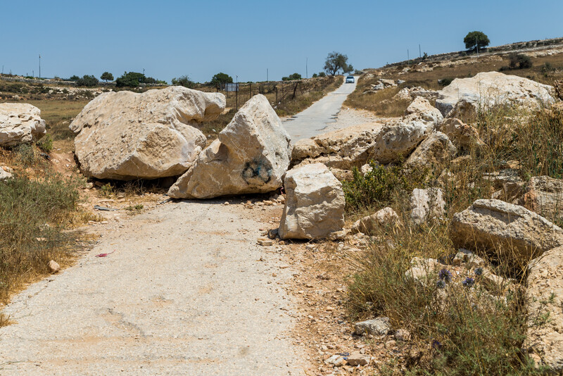 Large boulders block dirt road