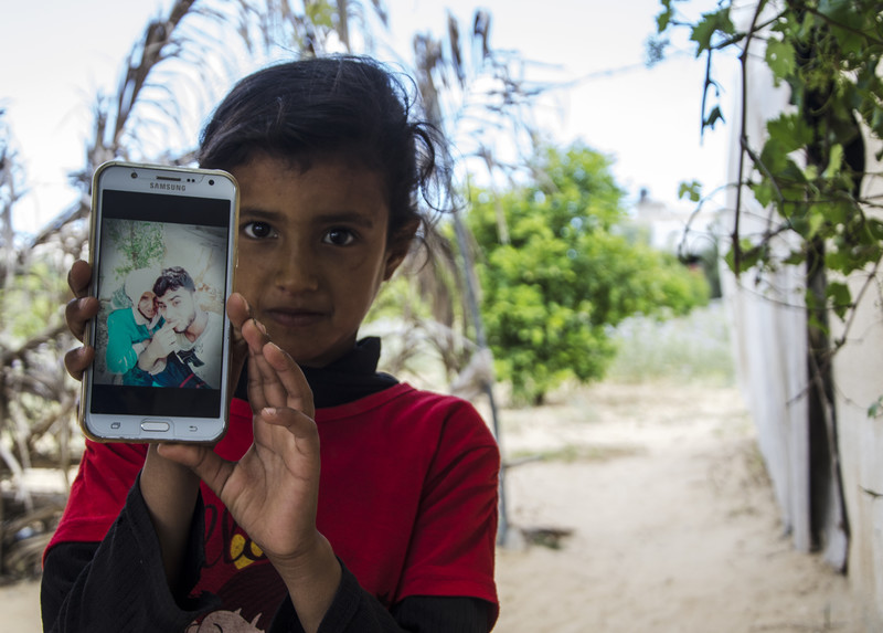 Girl displays a mobile phone showing a photo of older woman and youth