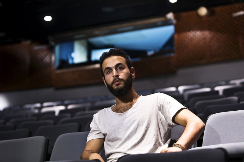 Young man sits in row of empty seats in theater